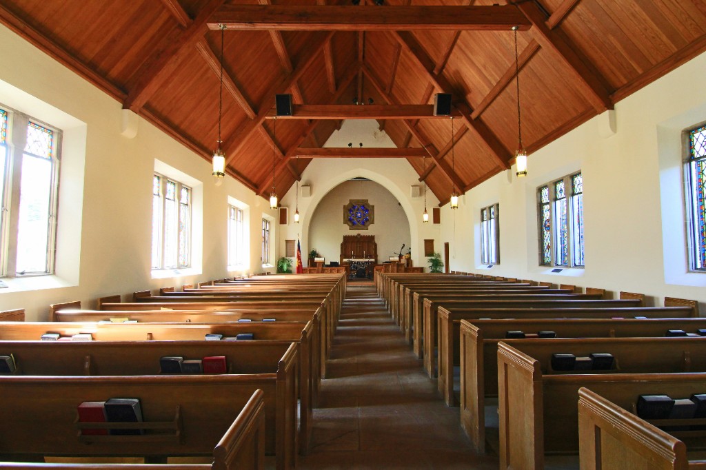 Church sanctuary interior—wooden pews and center aisle leading toward the altar