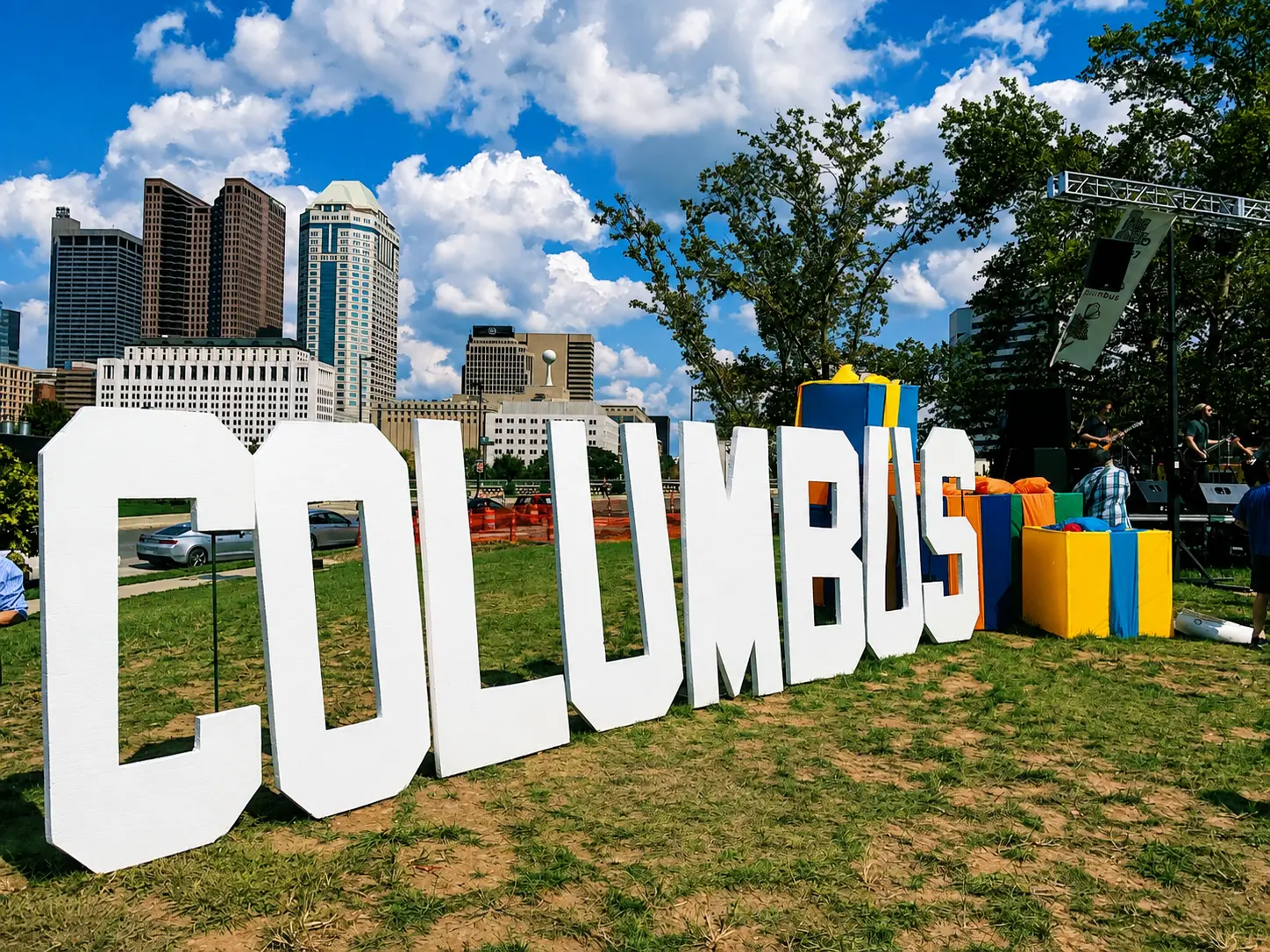 The COLUMBUS sign on the grass downtown, with the city skyline behind it