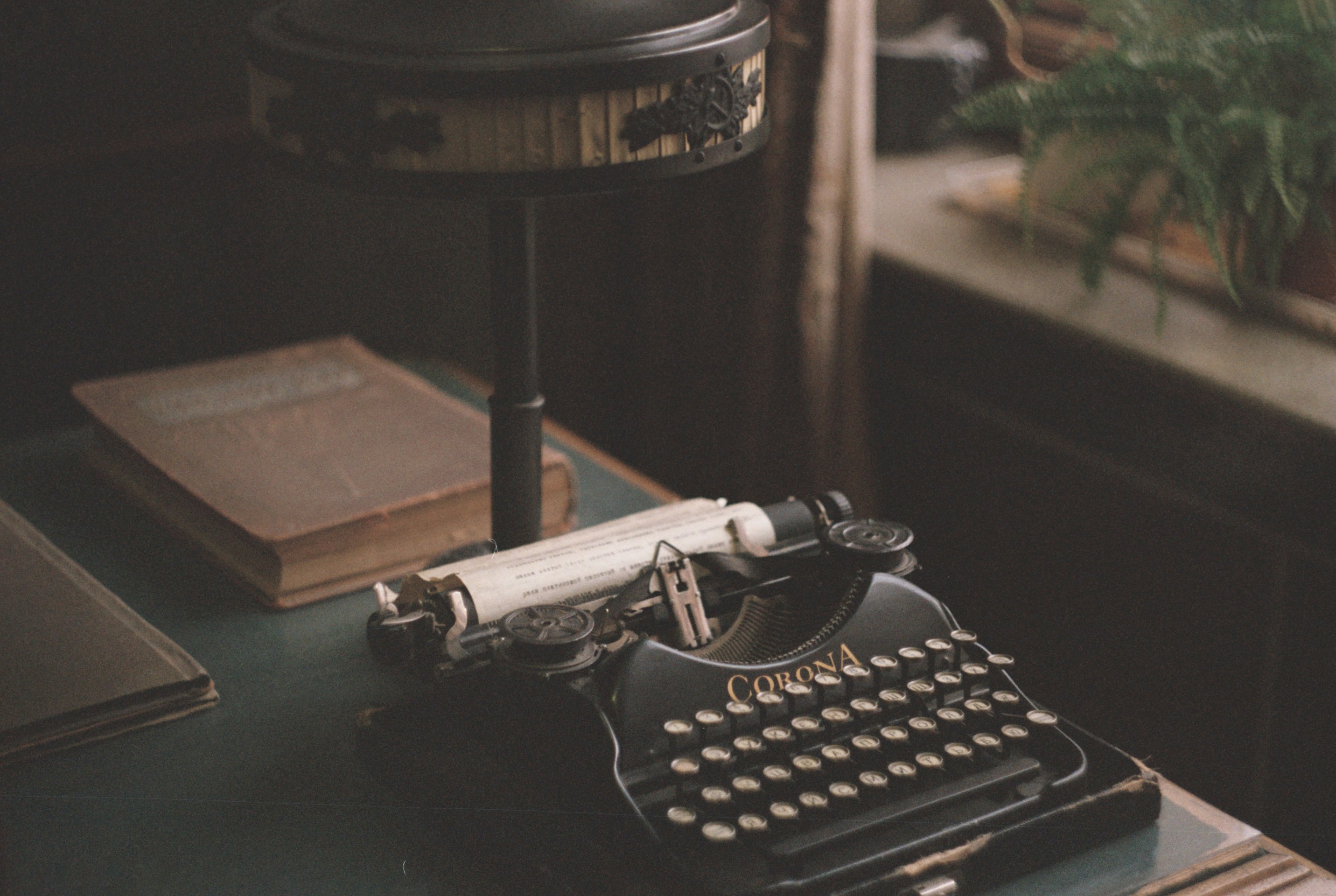 Vintage typewriter on a desk with books and a desk lamp