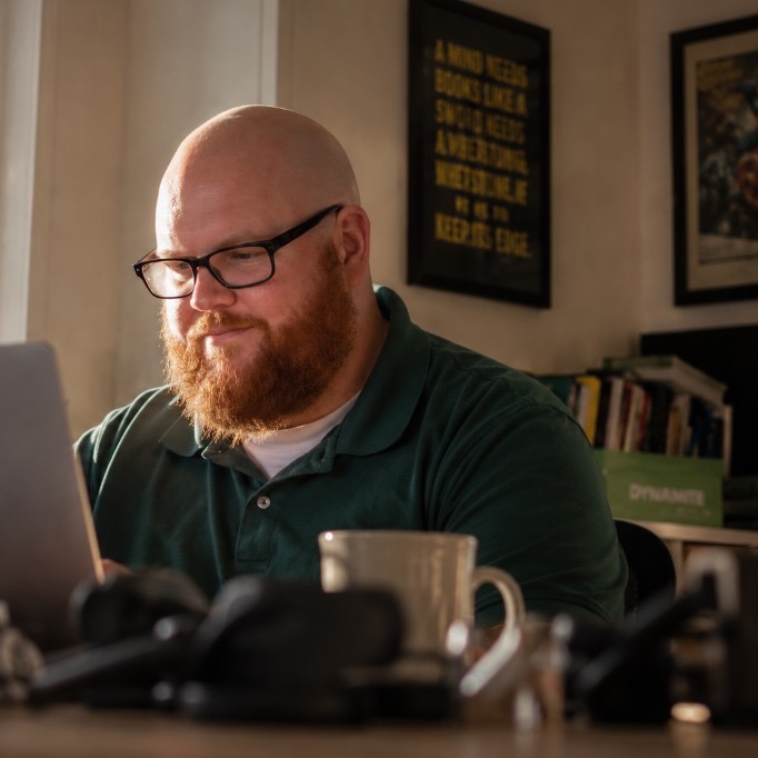 Phil working at a desk with natural light from the window